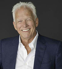 A man with white hair and wearing a suit.